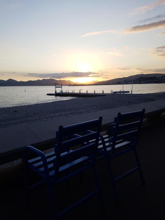 un banco sentado en la playa con la puesta de sol en el fondo en ++++ renovated cosy 50m2 sunny flat / balcony / close to beach and to the Palais des festivals ++++, en Cannes