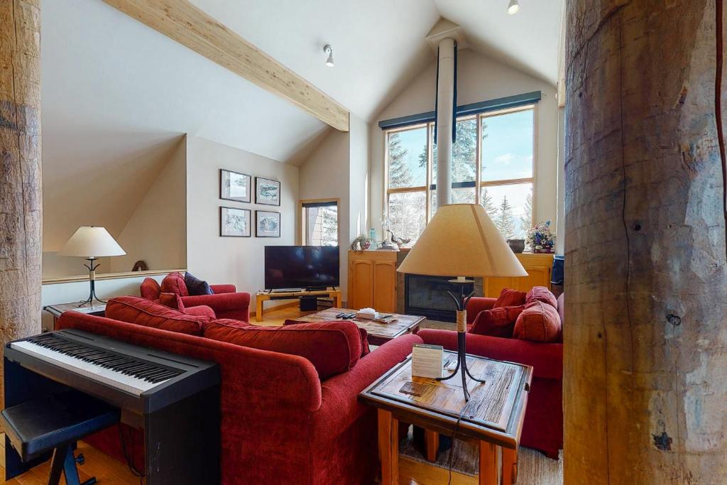 a living room with red couches and a piano at Cool Ridge Town Home at Summerwood in Keystone