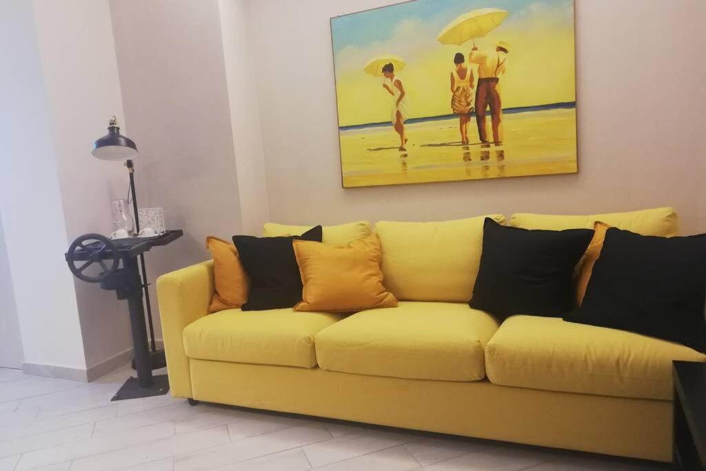 een gele bank in een woonkamer met een schilderij bij Palazzo D'Arrigo Black Loft in Catania