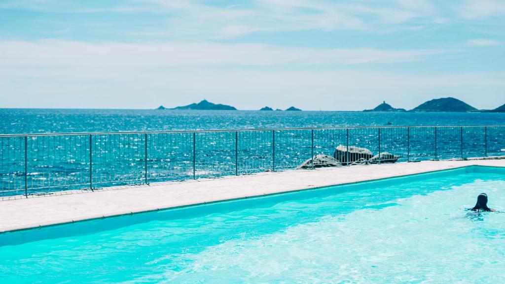 een persoon in een zwembad naast de oceaan bij Hôtel Cala di Sole in Ajaccio