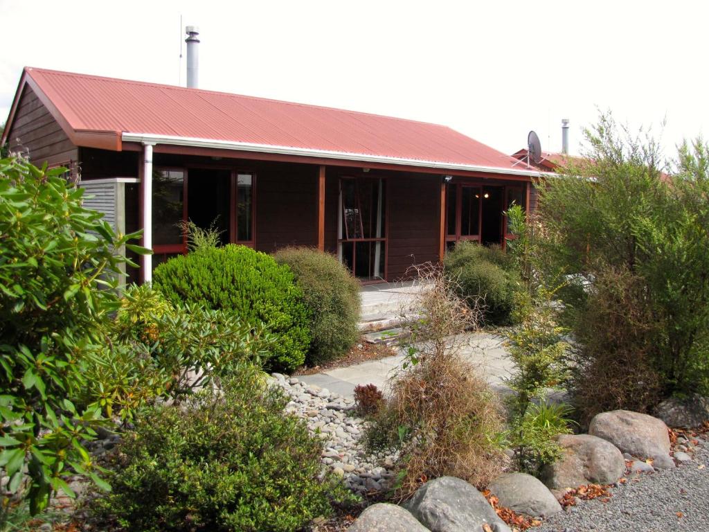 una casa con un tetto rosso e alcuni cespugli di Alpine Cabin - Ohakune Holiday Home a Ohakune