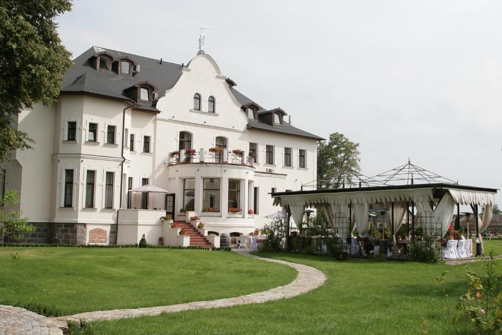 uma grande casa branca com um jardim relvado em Hotel Usadba em Kaliningrado