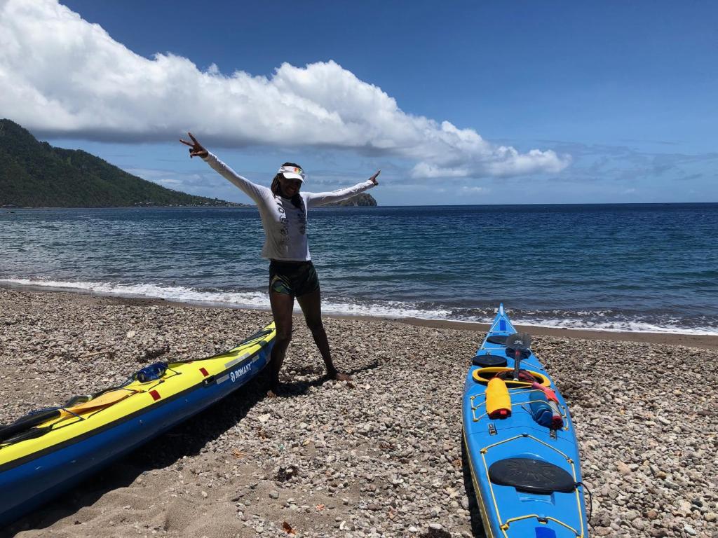 a woman standing on a beach next to two kayaks at Soufriere Guesthouse in Soufrière