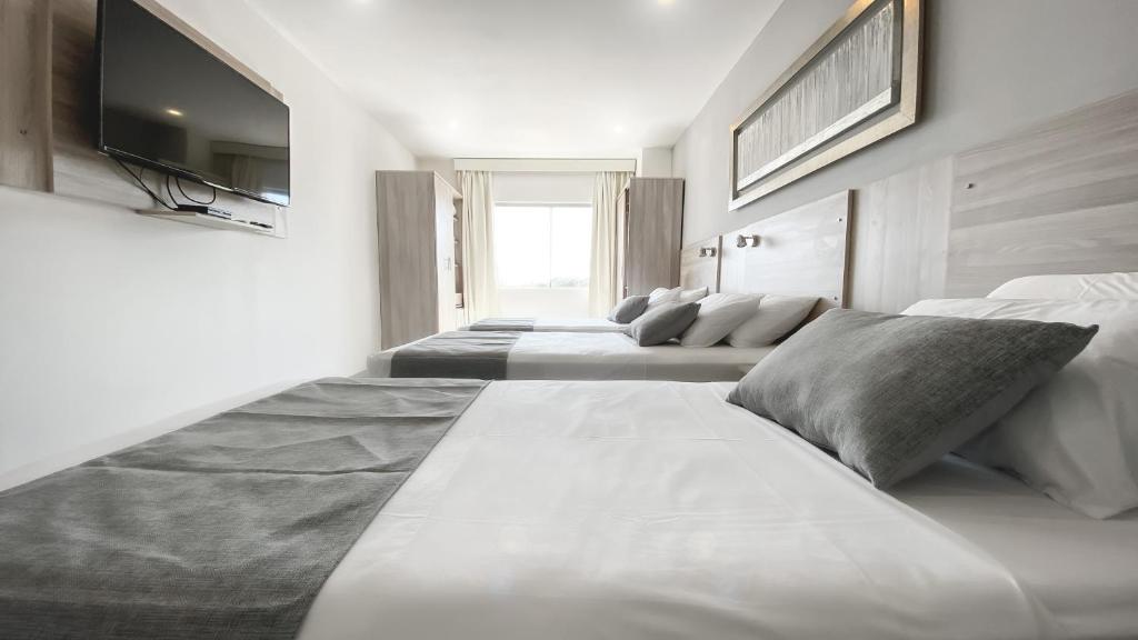 um quarto com 4 camas e uma televisão de ecrã plano em Danieri Asunción Hotel em Assunção