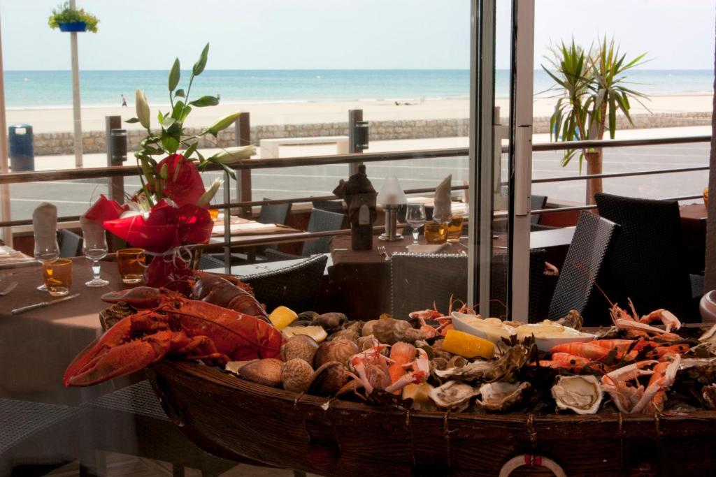 a basket of seafood on a table near the beach at Logis Hôtel Mediterranee in Port-la-Nouvelle