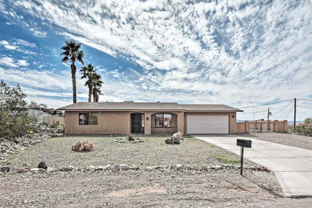 a house with a palm tree in front of it at Single-Story Home with Yard, 1 Mi to Windsor Launch! in Lake Havasu City