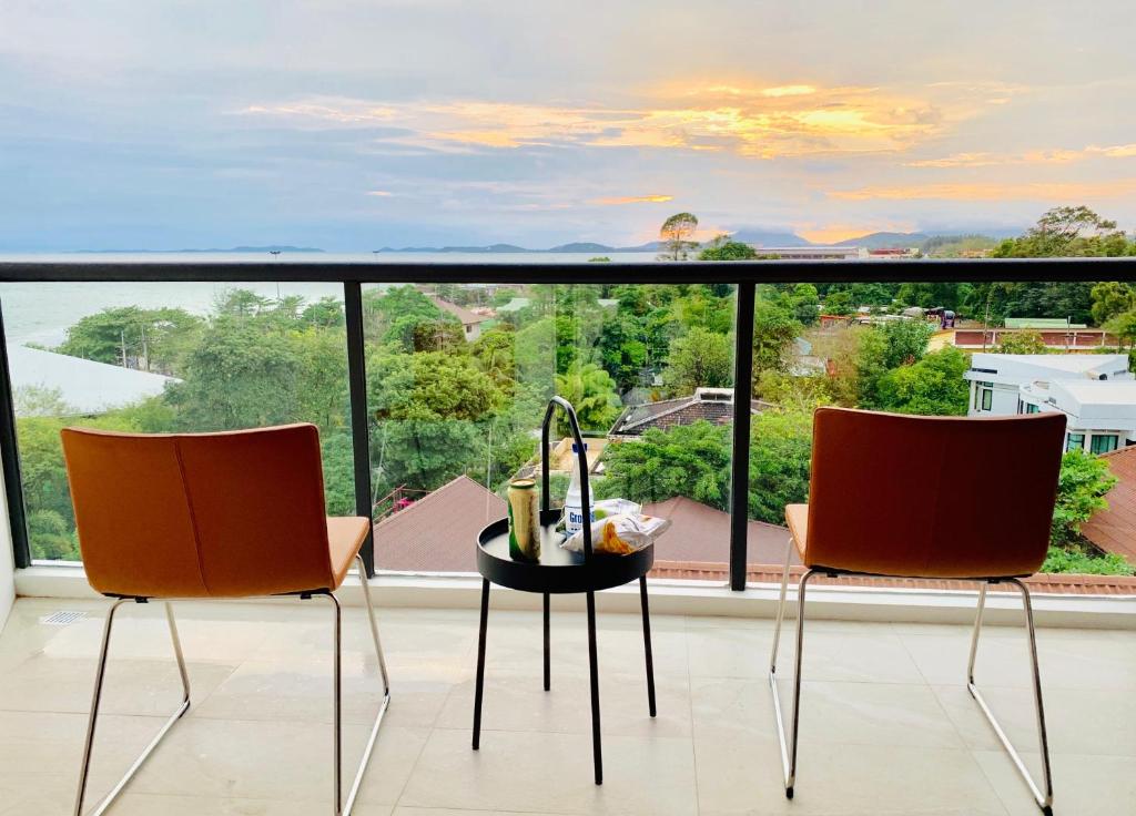 two chairs and a table in front of a large window at Top Floor Gorgeous Sunset View - Mae Phim Beachfront Condo in Mae Pim