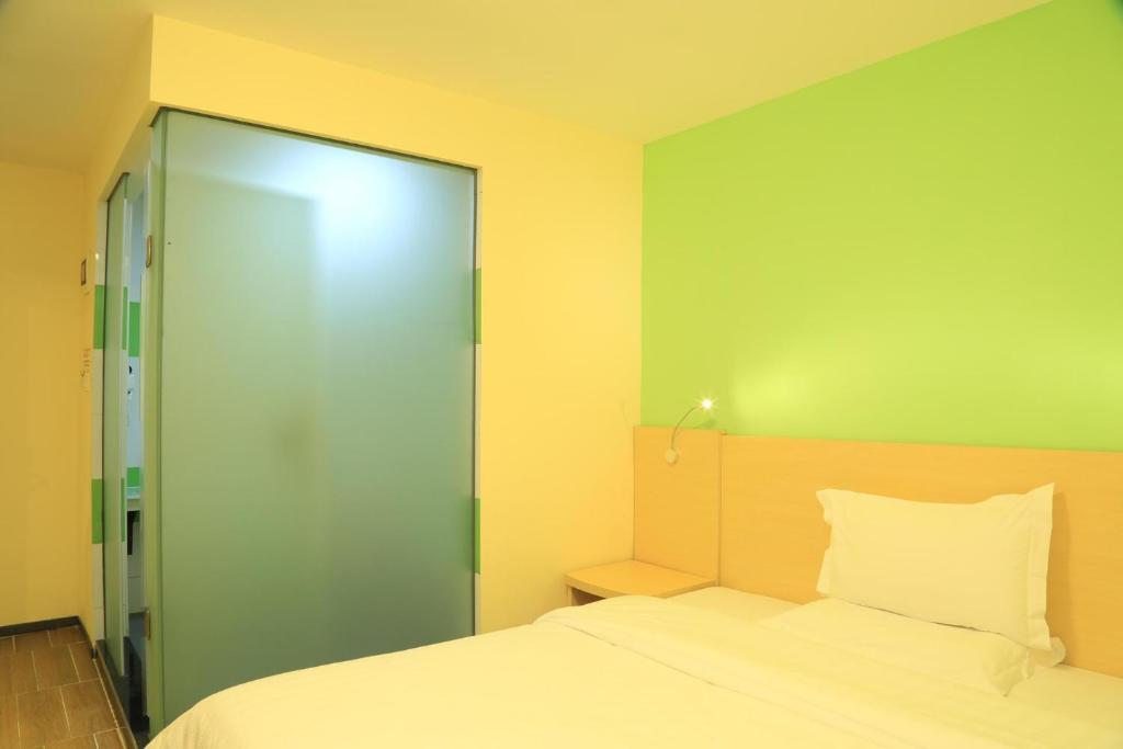 a bedroom with a bed and a sliding glass door at 7Days Inn Guiyang Ergezhai in Guiyang