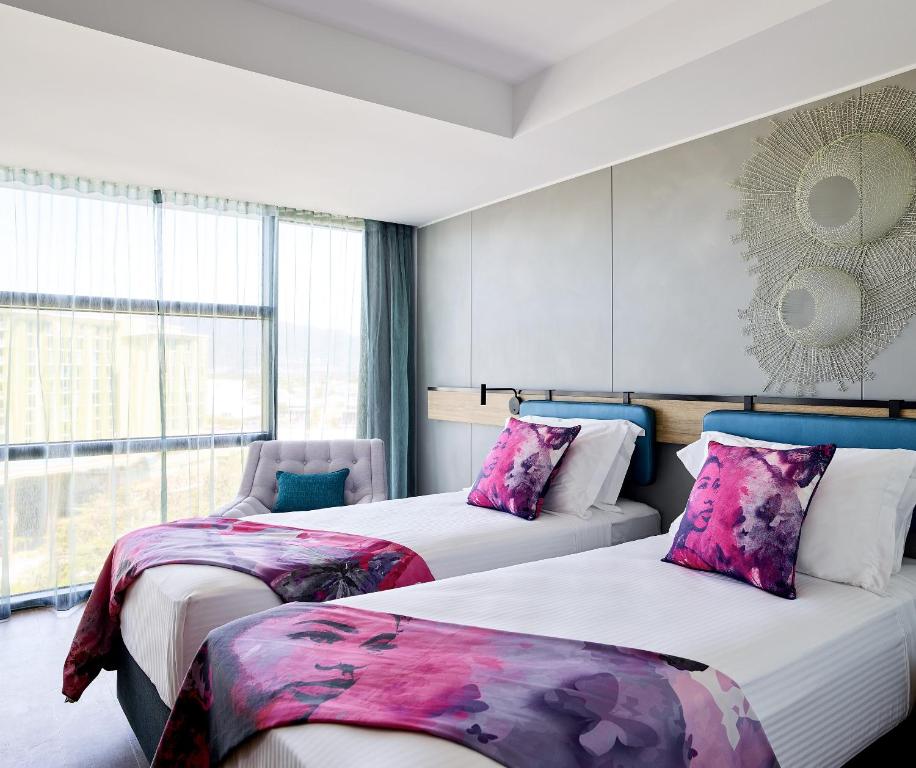 a hotel room with two beds and a window at Crystalbrook Flynn in Cairns