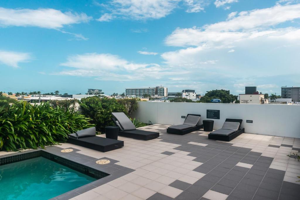 a patio with lounge chairs and a swimming pool on a roof at Airtrip Apartments on River Street, Mackay in Mackay