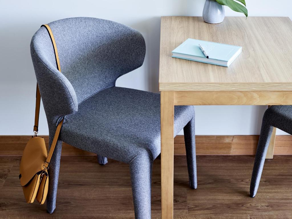 a chair next to a wooden table with a desk at Crystalbrook Flynn in Cairns