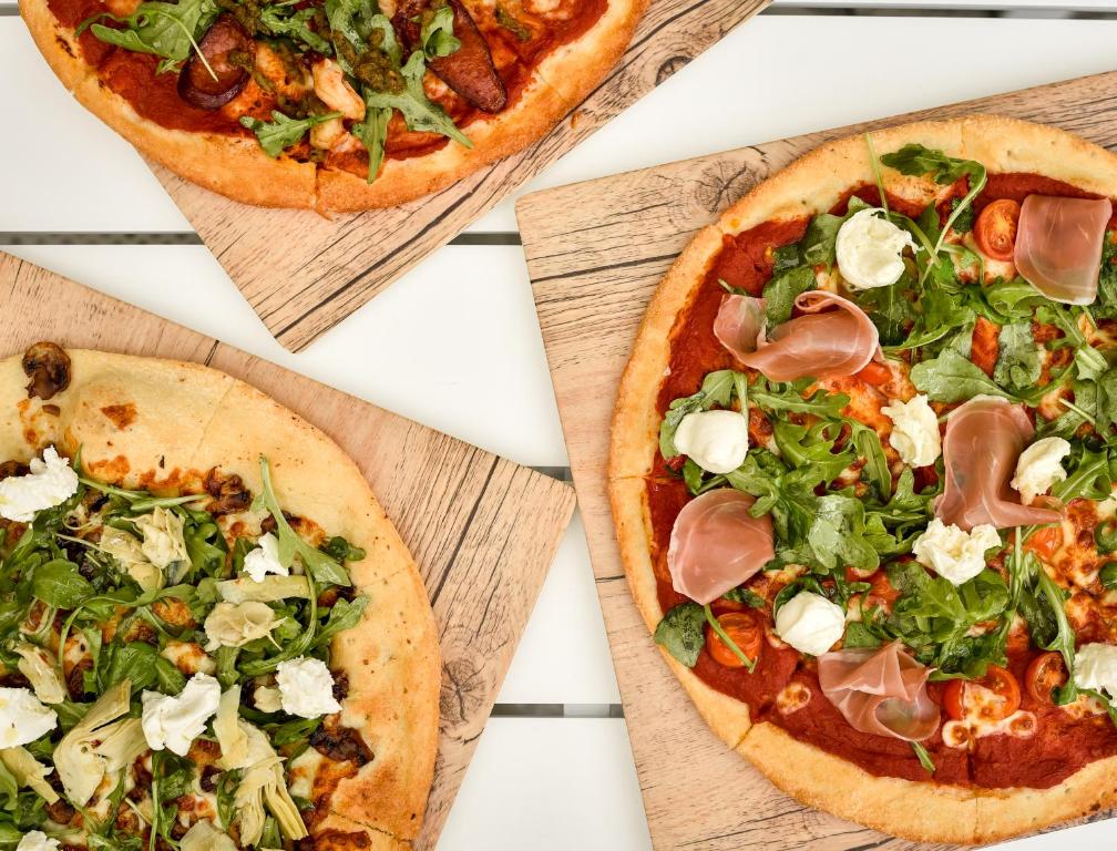 three pizzas on wooden cutting boards on a table at Crystalbrook Flynn in Cairns