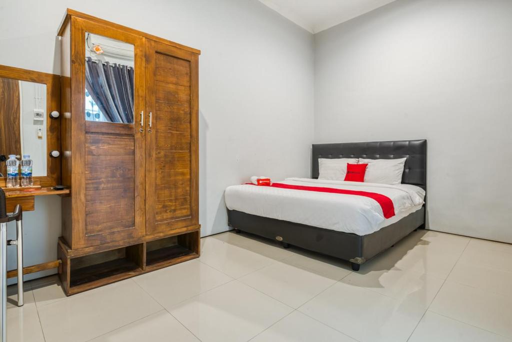 Schlafzimmer mit einem Bett und einem Holzschrank in der Unterkunft RedDoorz near Surabaya Zoo in Surabaya