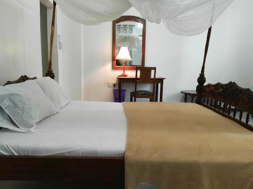 a bedroom with a bed with white sheets and a mirror at Sharook Riviera Grand Lodge in Wete