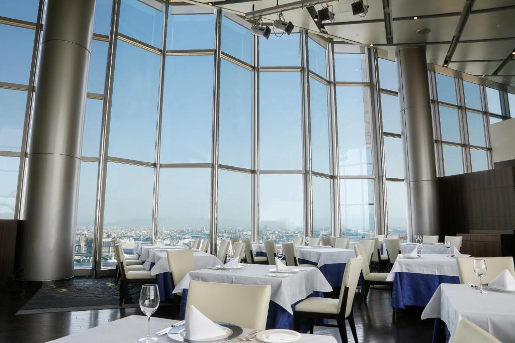 a restaurant with white tables and chairs and large windows at Hotel Keihan Universal Tower in Osaka