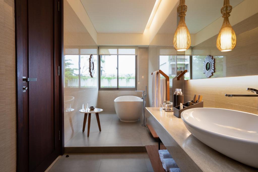 a bathroom with a white tub and a sink at MERUSAKA Nusa Dua in Nusa Dua