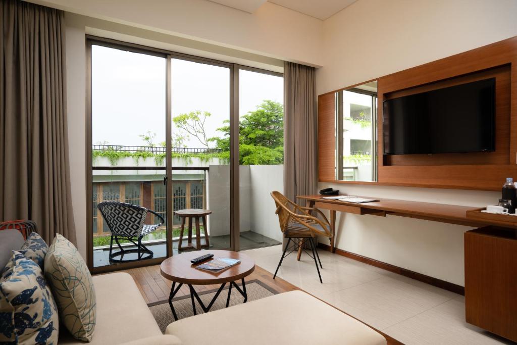 a living room with a couch and a desk with a television at MERUSAKA Nusa Dua in Nusa Dua