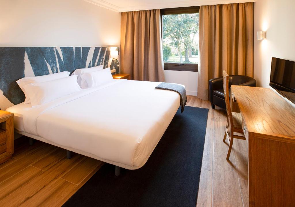
a hotel room with a large bed and a large window at Hotel Eden Park by Brava Hoteles in Riudellots de la Selva
