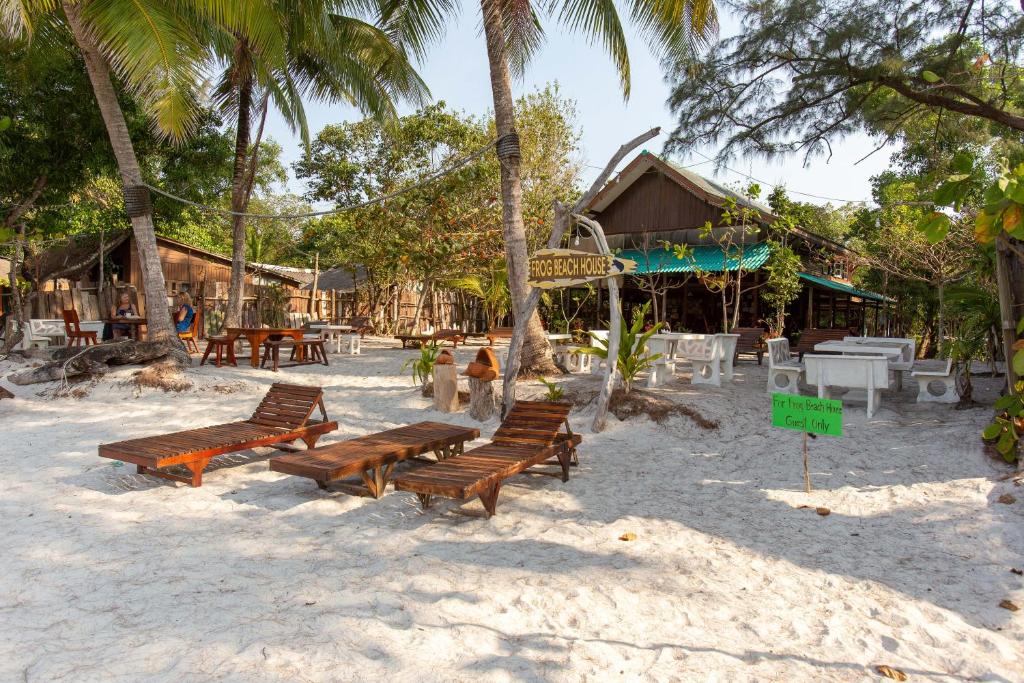 a group of benches sitting on the sand on the beach at Frog Beach House in Ko Phayam