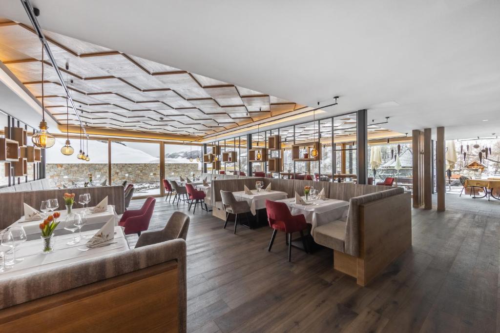 jadalnia ze stołami, krzesłami i oknami w obiekcie Almhotel Glieshof w mieście Malles Venosta