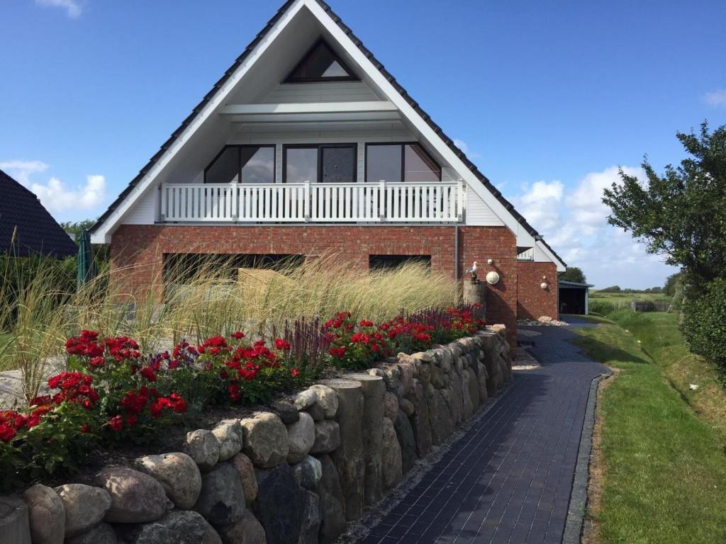 ein Haus mit einer Steinwand und Blumen in der Unterkunft Nickelshus Whg. Robin in Sankt Peter-Ording