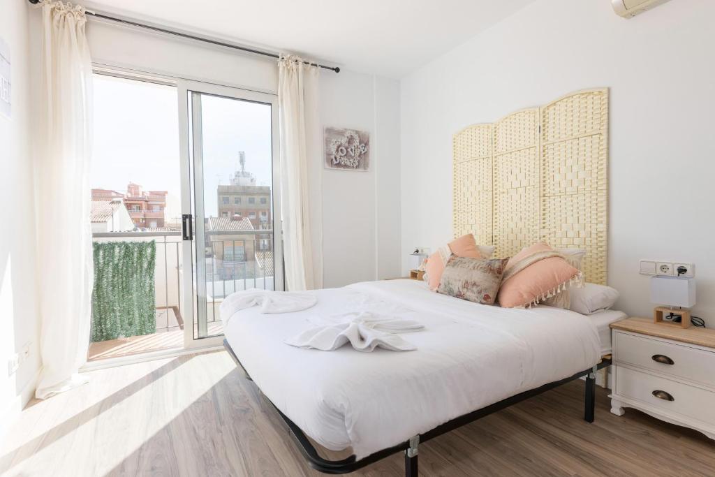 a white bedroom with a bed and a large window at matarolux18 in Mataró