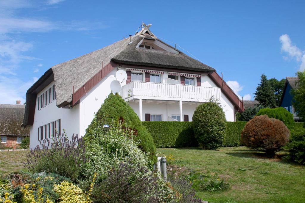 Groß ZickerにあるHaus am Boddenの白いバルコニーと茂みのある白い家