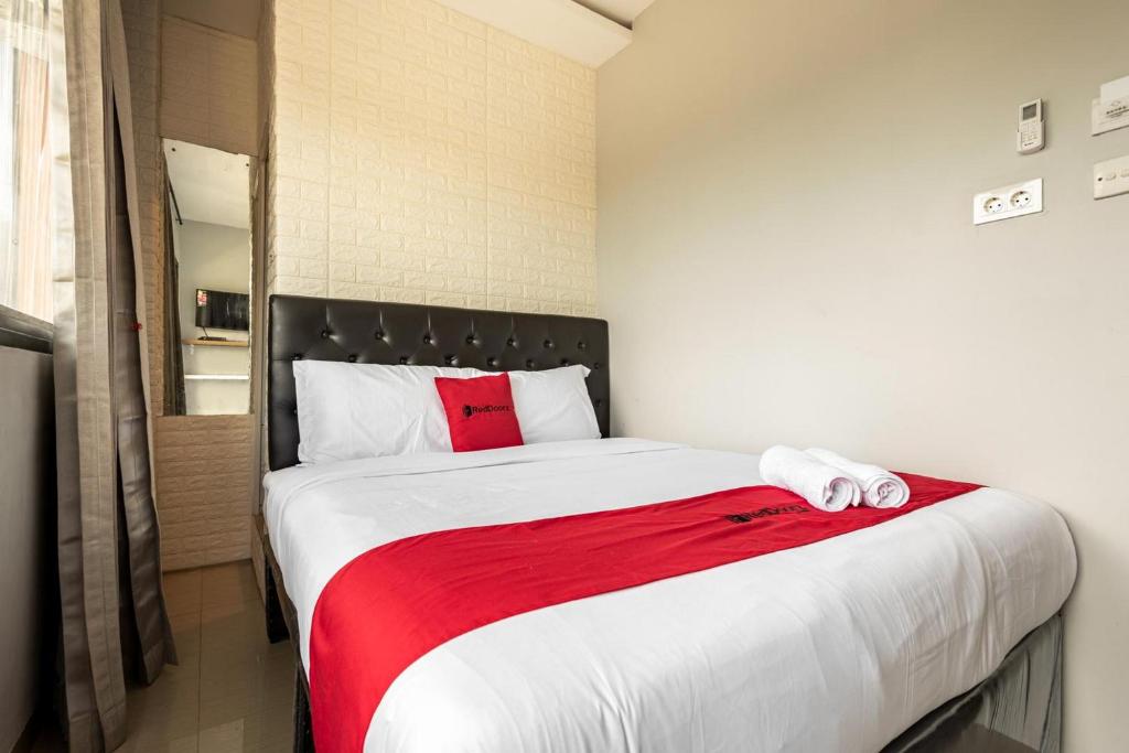 - une chambre avec un grand lit et une couverture rouge dans l'établissement RedDoorz near Tanjung Duren 2, à Jakarta