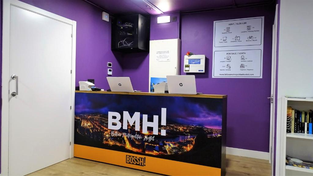 ビルバオにあるBilbao Metropolitan Hostel by Bossh Hotelsの紫の壁の上にノートパソコンを配置したデスク