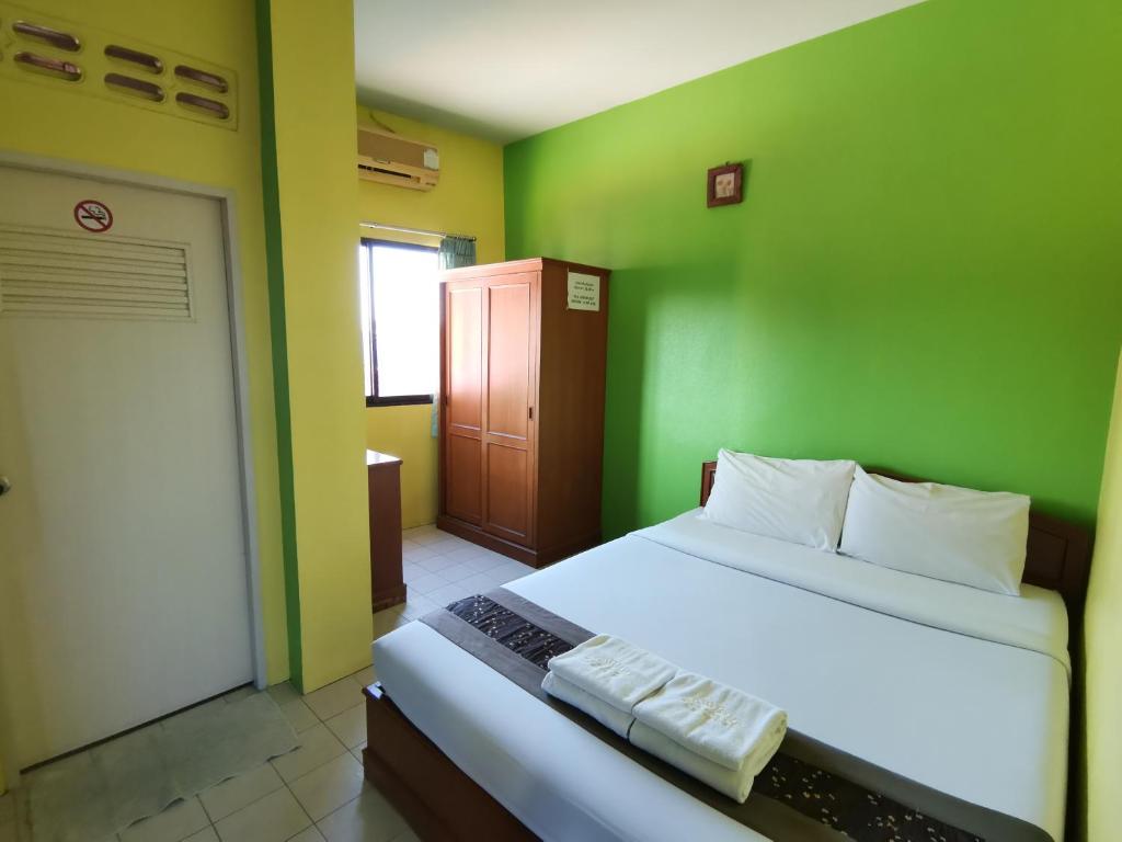 um quarto com paredes verdes e uma cama branca em Samran Residence em Krabi