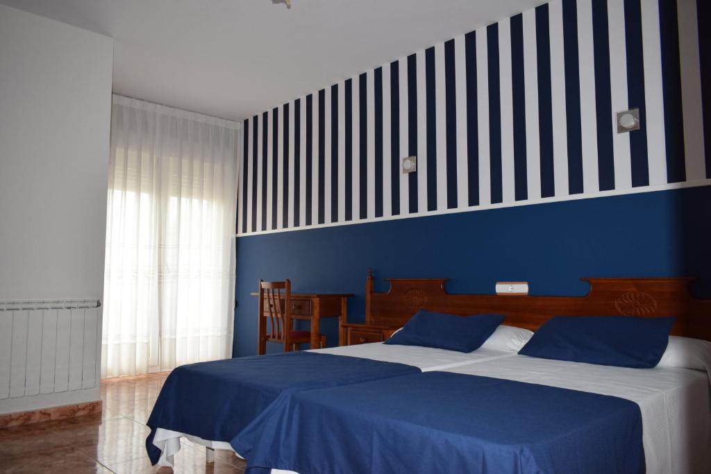 a bedroom with a bed with a blue wall at Hotel VIDA Ostra Marina in Sanxenxo