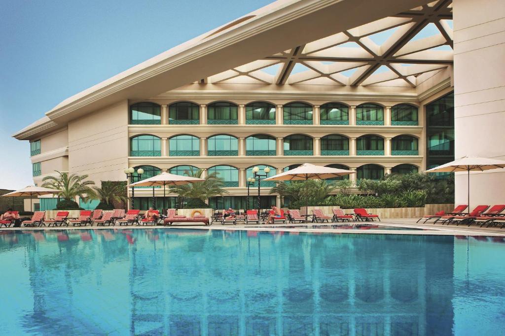 a swimming pool in front of a hotel at Mövenpick Grand Al Bustan in Dubai