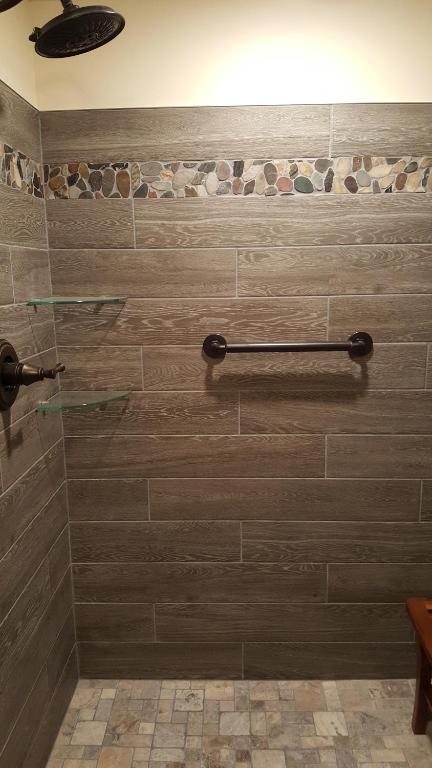 a bathroom with a shower with brown tiles at Bear Cove Inn in Saint Ignace