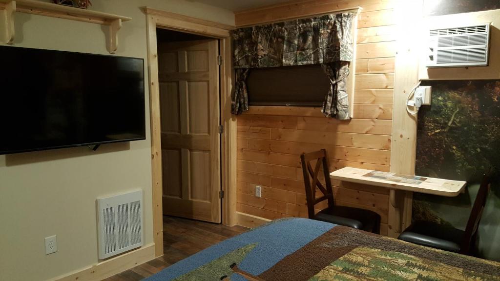 a bedroom with a bed and a television on a wall at Bear Cove Inn in Saint Ignace