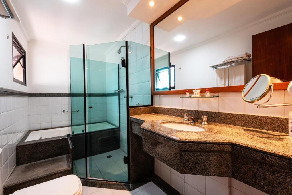 a bathroom with a glass shower and a sink at Summit Suítes Hotel Jundiaí in Jundiaí