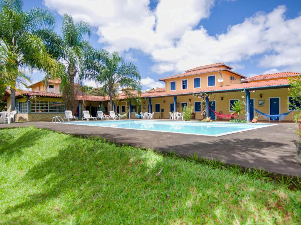 a villa with a swimming pool in front of a house at OYO Pousada Estrada Das Águas, São João del Rei in São João del Rei