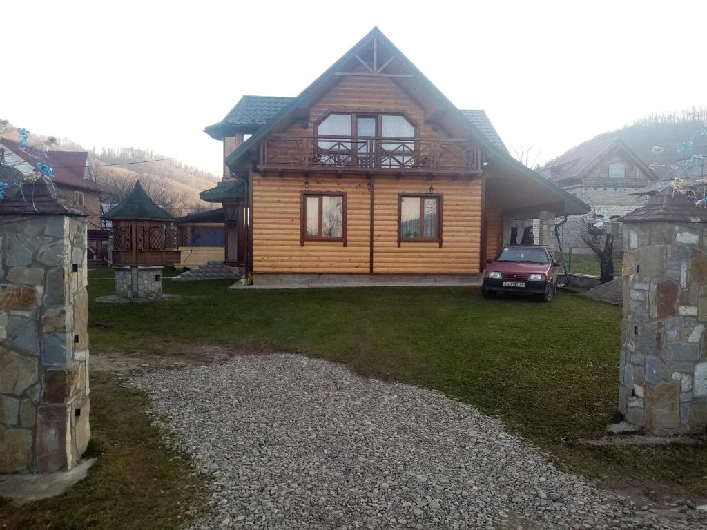 a log house with a car parked in front of it at Садиба Федорчуків Гірська хатина in Sheshory