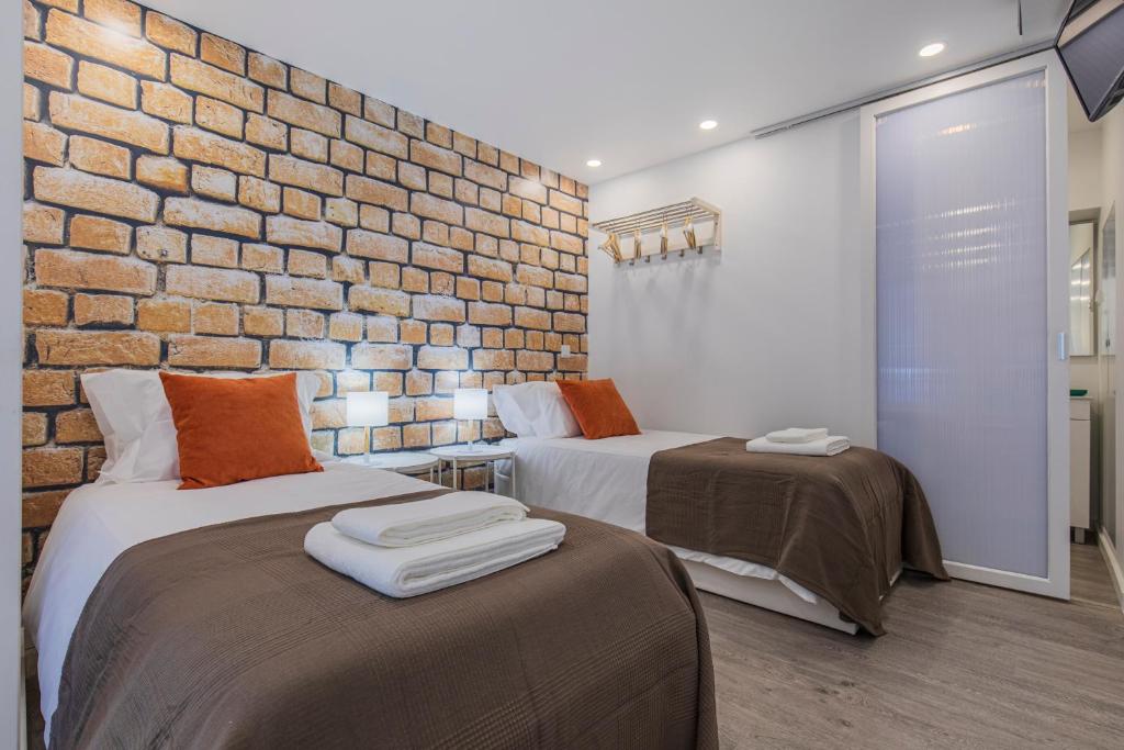 duas camas num quarto com uma parede de tijolos em Studio in Alfama by Lucky Surface em Lisboa