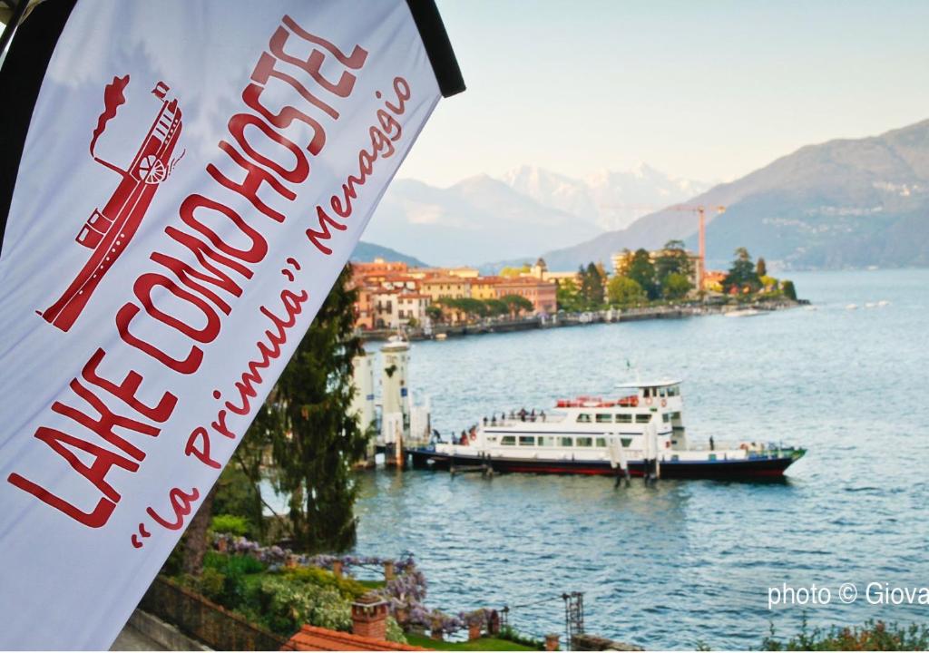 a boat on the water with a sign in front of it at Lake Como Hostel in Menaggio