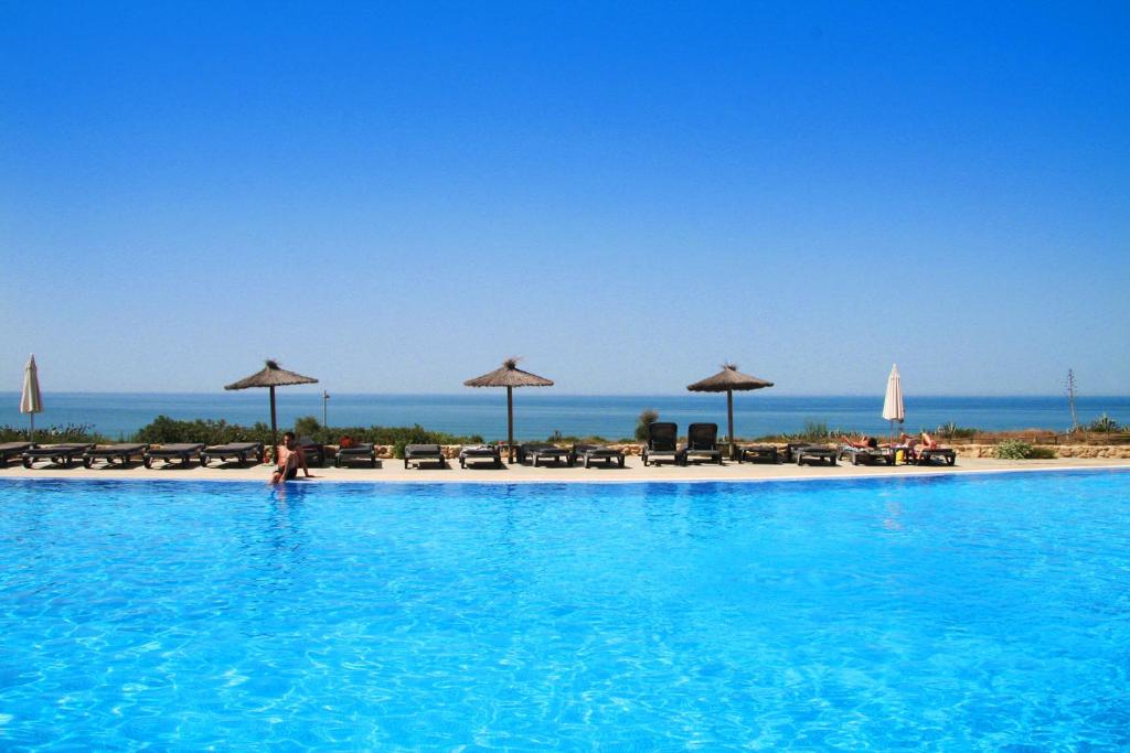 a swimming pool with a beach and umbrellas at Garbí Costa Luz in Conil de la Frontera