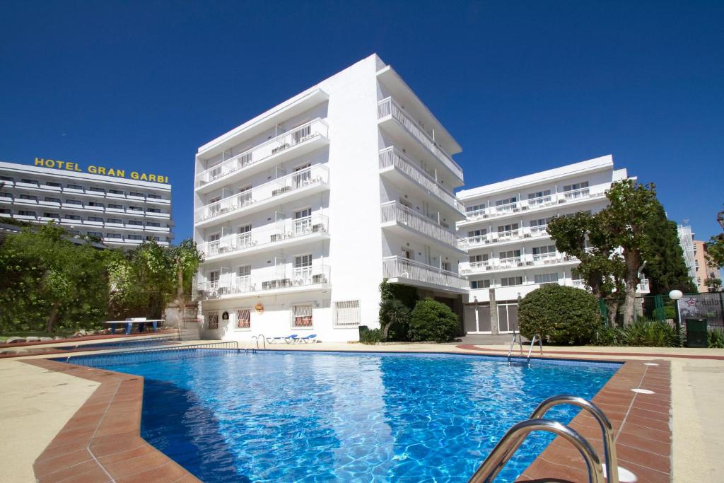 um hotel com piscina em frente a um edifício em Hotel Villa Garbí em Lloret de Mar