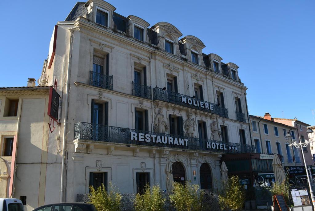 un gran edificio blanco con un cartel. en Le Grand Hôtel Molière, en Pézenas