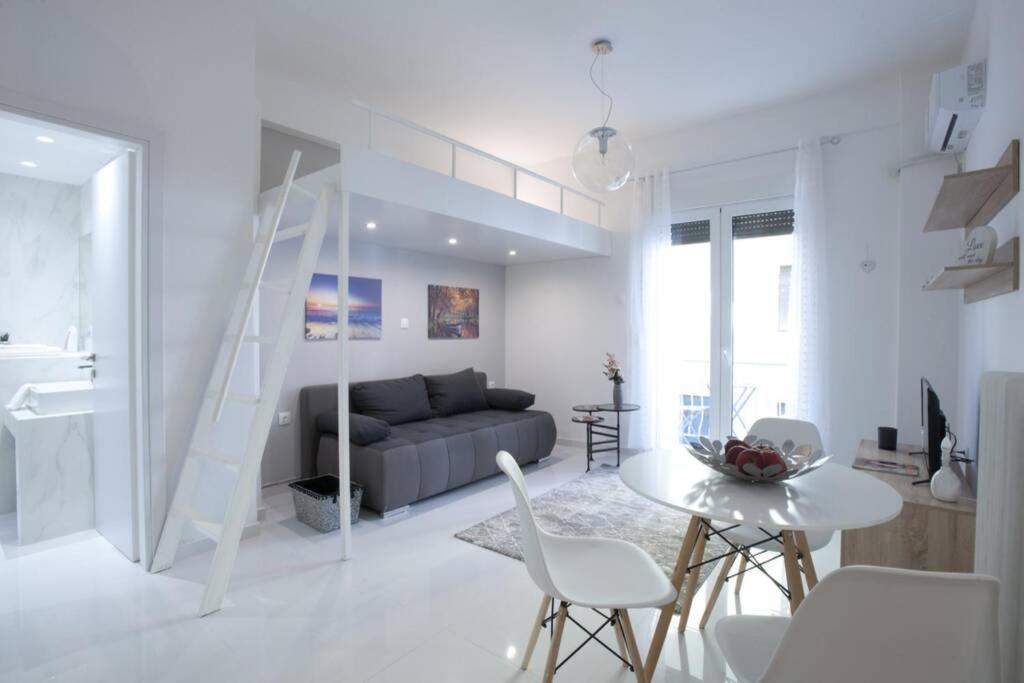 uma sala de estar branca com um sofá, uma mesa e cadeiras em Victoria Sq., A cozy and stylish apartment em Atenas