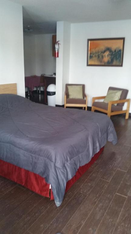 a bedroom with a large bed and two chairs at Rimbey Motor Inn in Rimbey