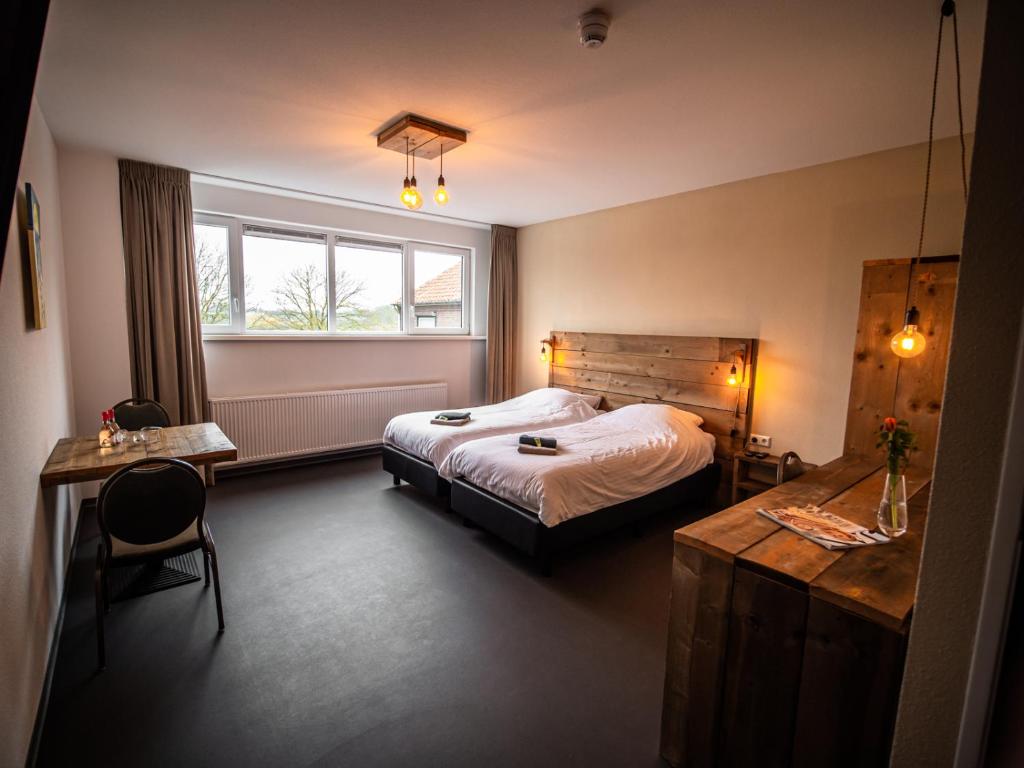 a bedroom with a bed and a desk and a window at B&B bij de 3 linden in Wijchen