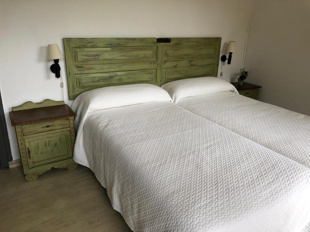 a bedroom with a large white bed and a wooden headboard at CASA RURAL DOSAL in Ruiseñada
