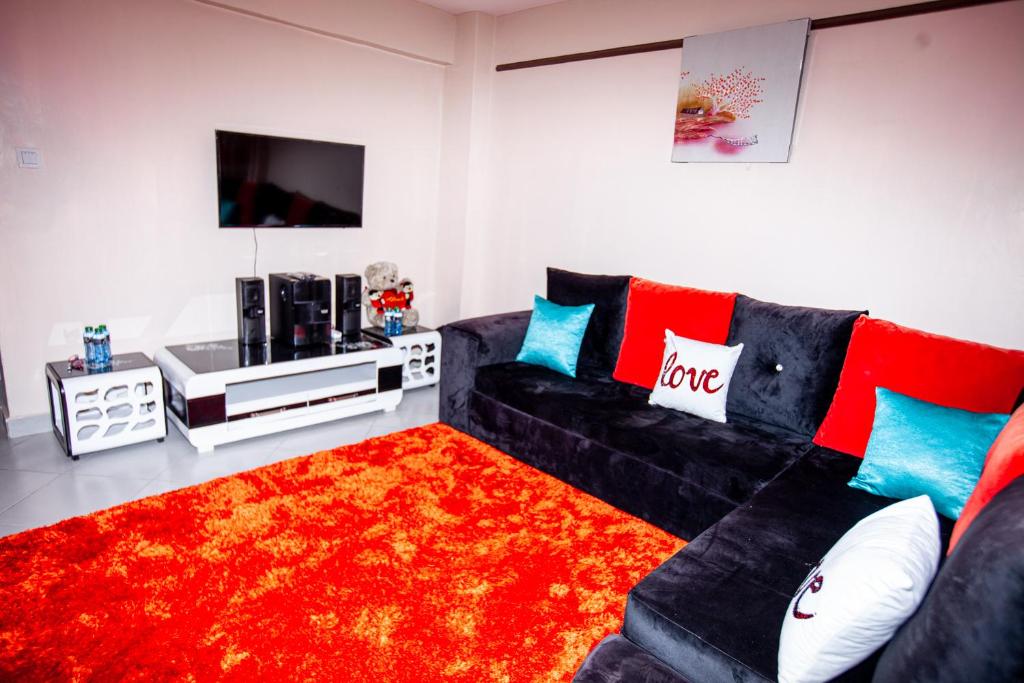 sala de estar con sofá negro y alfombra roja en JJ Homes - Podium Heights Apartment Nairobi en Nairobi