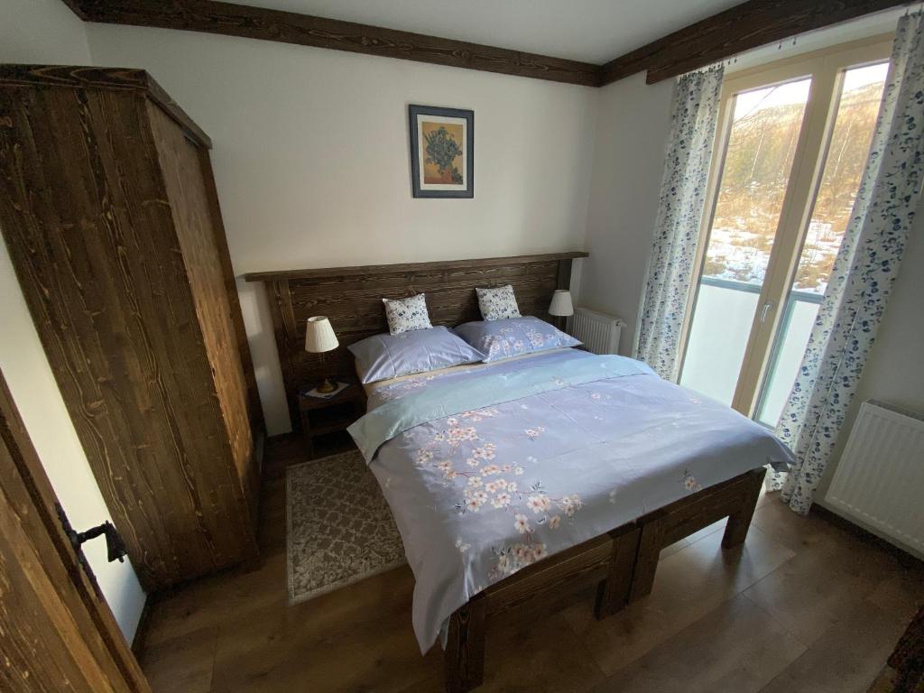Schlafzimmer mit einem Bett mit einem Kopfteil aus Holz und einem Fenster in der Unterkunft Apartmány Veternica v Bernarde in Nový Smokovec
