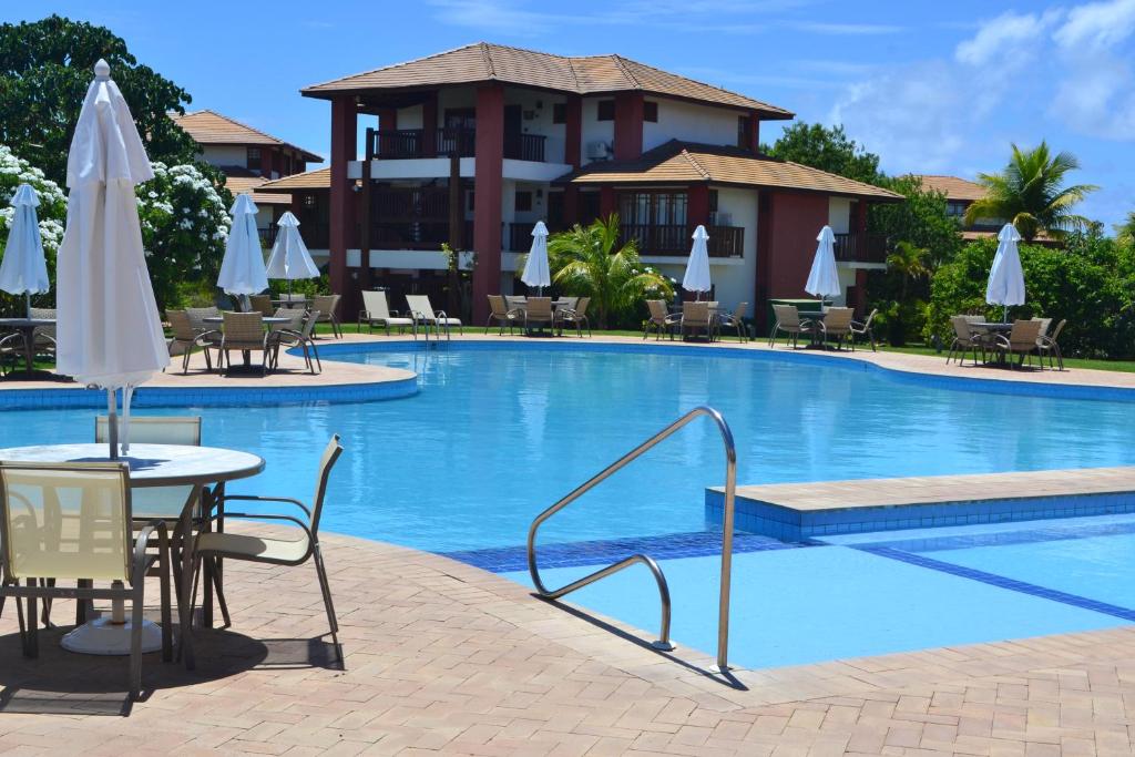 una piscina con mesas, sillas y sombrillas en Praia do Forte, Piscinas Naturais, en Praia do Forte