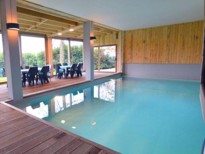 a swimming pool in a house with a table and chairs at Charming farmhouse in Waimes with swimming pool and sauna in Waimes